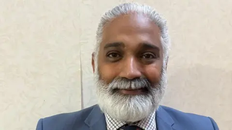 Lancashire County Council A man in a suit with a large bushy white beard smiles