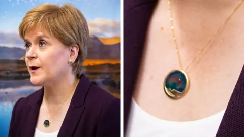 Getty Images A composite image of Nicola Sturgeon wearing a necklace with a large gold pendant, inlaid with blues, reds and greens. There is a close up of the necklace on the right hand side. 
