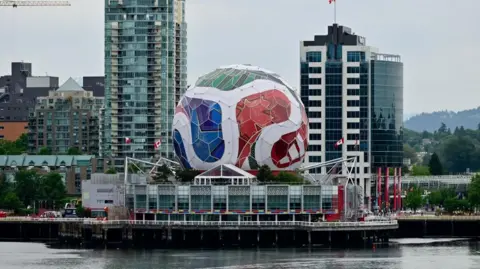 Reuters A giant Fifa football in white, red, green and blue sits atop the Vancouver science centre and against the city skyline. 
