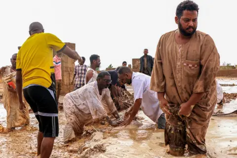 AFP men build a temporary dam made of mud bricks amid flooding in the Messawi area near Meroe.