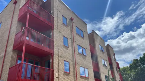 A new block of flats at the Broadfields Estate in Edgware. Beige coloured bricks with red balconies and window frames