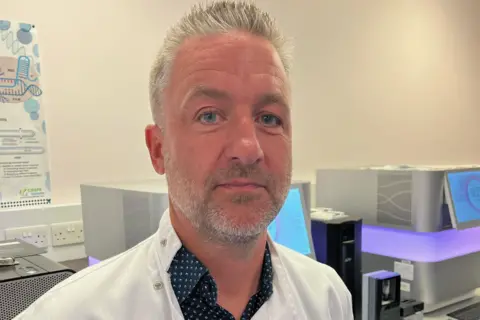 Prof Jim Wilson in his research lab, wearing a white coat