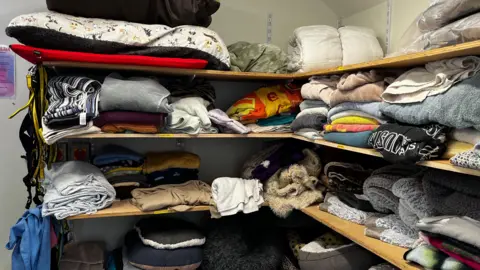 Jack Maclean/BBC Shelves full of bedding, towels and duvets.