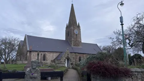 A wide shot of St Martins Church. It is a very old building, with brick walls and a slate roof.