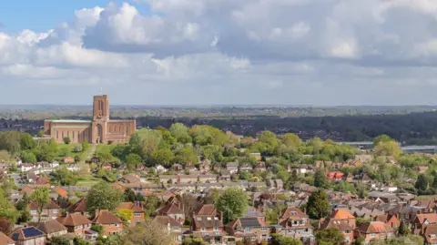 A Surrey town pictured from afar. It is leafy and green. 