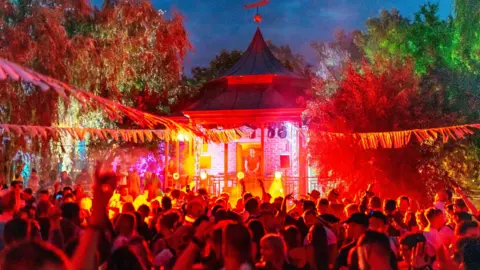 Andrew Whitton Crowds attend a small stage with a DJ playing