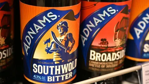 Getty Images چهار بطری آبجو Adnams در یک قفسه، یکی به نام Southwold Bitter و دیگری به نام Broadside