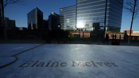 Getty Images The name of Elaine McIver is engraved in gold on a marble slab, with buildings and the glinting sun in the background