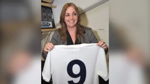 Supplied Dawn Astle smiles as she holds up her dad's No 9 football shirt