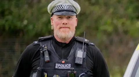 An image of PC James Mahony throughout his career while out on dury. He is wearing his uniform and smiling for the camera.