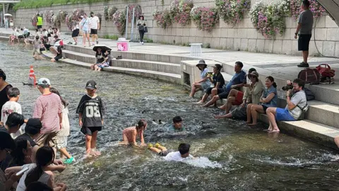 Getty Images Local residents and tourists cool off at Cheonggyecheon stream
