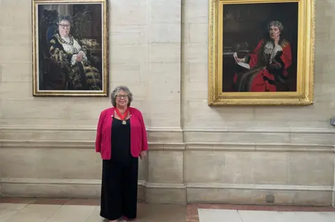 Councillor Jacqui Rayment stood between her portrait and that of Lucia Foster Welch.