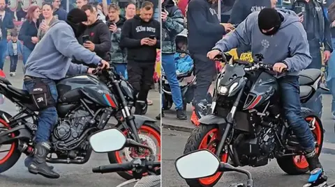 Two pictures side-by-side of a balaclava-clad biker who appears to be spinning around on the back wheel of his motorbike while a crowd looks on. The pictures capture him at different points in the spin. He is on powerful a red and black motorbike and is also wearing dark blue jeans and a grey/blue hoodie. 