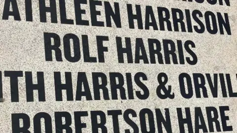 LDRS Close up of Rolf Harris's name as it appeares on the carpet. It is in a centred list of entertainers and is in a plain capilalised font in black on a white grainy background