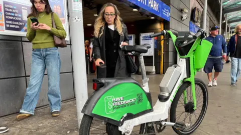 A white and green bike is parked in front of a Tube entrance