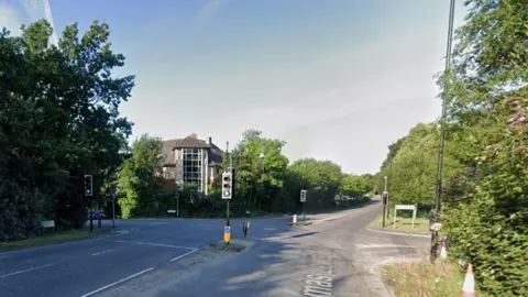 Road junction with dual carriageway running along and a road also running across between sets of traffic lights.
