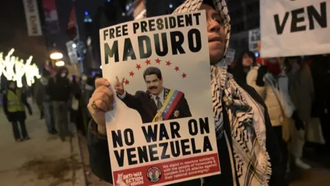 Woman holds poster at protest in Chicago which says "FREE PRESIDENT MADURO - NO WAR ON VENEZUELA"