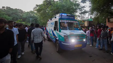 An ambulance makes its way past fans of the Royal Challengers Bengaluru (RCB) on a street outside the M. Chinnaswamy Stadium on June 04, 2025 in Bengaluru, India.
