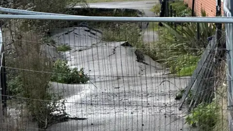 We Love Peterborough The footpath now buckled and cracked with vegetation growing out of the gaps in the tarmac, the path is fenced off from the public with Heras building fences about 2m (6ft) high.