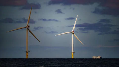 PA Media Wind turbines in sea with ship alongside