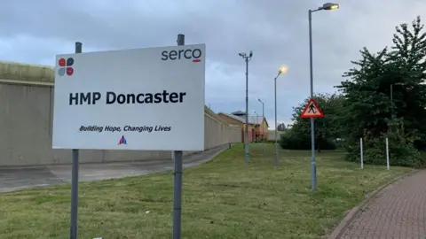 BBC A sign outside HMP Doncaster that reads "HMP Doncaster: Building hope, changing lives".