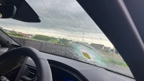 A large hole in a the front window of a car