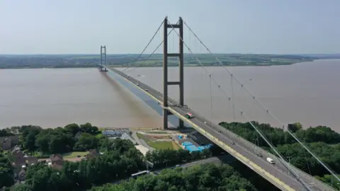 PA Media Aerial view of the Humber Bridge showing the bridge spanning the muddy water with vehicles crossing.

