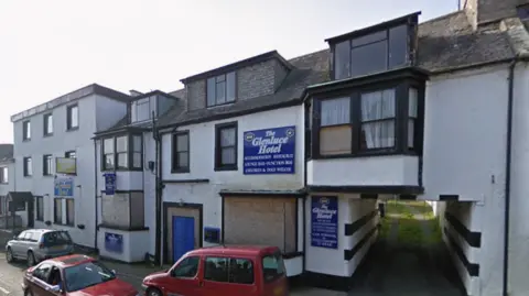 Google The old Glenluce Hotel with some windows already boarded up and cars parked outside