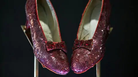 Getty Images A pair of famous Ruby slippers from the movie 'The Wizard of Oz'. They are displayed on a blackground.