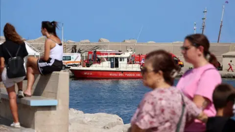 Reuters People watch rescue teams near the site of the sunken yacht