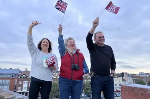 Three people on the round tower, Portsmouth waving flags