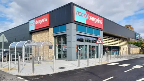 Home Bargains' store in Dingwall. There is a pedestrian crossing and shopping trolley shelters.