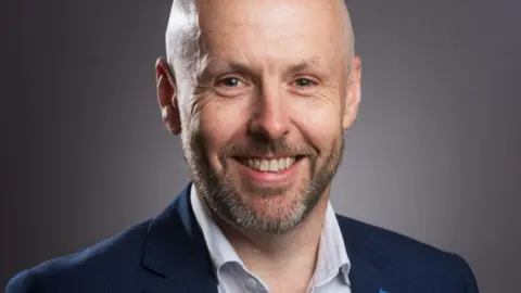 NHS Dumfries and Galloway A man in a suit smiles at the camera