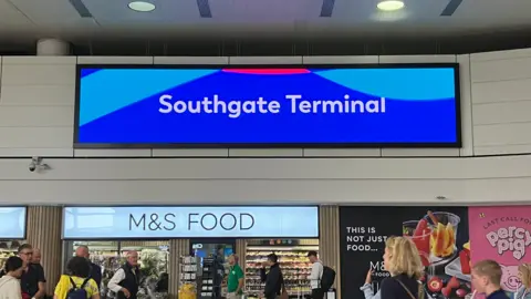 Gatwick Airport A large electronic sign at Gatwick Airport, over a supermarket, reading Southgate Terminal in white text