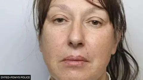 Lynne Leyson looks at the camera in this police photo, with her brunette hair tied back and hazel coloured eyes.