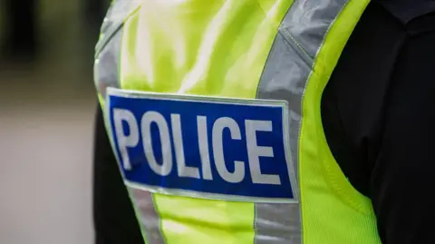Getty Images The back of a police officer, who is wearing a hi-vis jacket which has "police" written on the back of it
