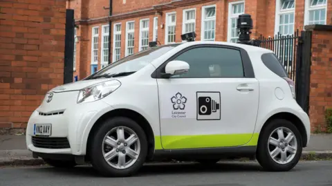 A small white car with a camera on top