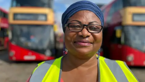 Woman with glasses and high vis jacket smiling at the camera.