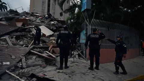 Municipal police officers stand next to the remains of a collapsed building after an earthquake in Caracas, Venezuela
