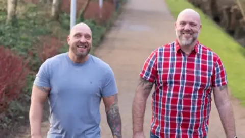 (left to right) Scott Allan and Gareth Evans. Both men are looking at the camera, Scott is in a blue t-shirt and Gareth has a red and blue short sleeve shirt on. 