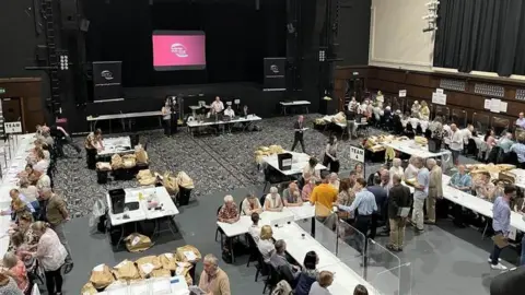 A room filled with people on white tables.