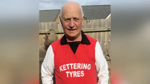 Bryan Lewin Bryan Lewin is wearing a replica of the 1976 Kettering Town kit. It is red with a black collar, white sleeves and "Kettering Tyres" printed in white font in the centre.