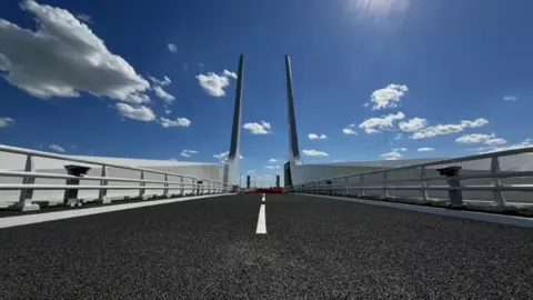Suffolk County Council The new Gull Wing Bridge in Lowestoft, showing road with metal railings on either side and vertical wing structures at the end