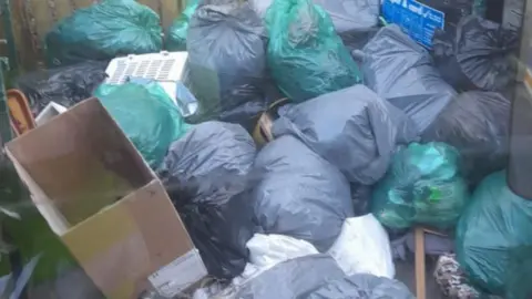 A pile of green and black rubbish bags