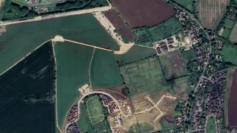 An aerial view of the land south of Eye Airfield where the new homes will be build. The landing strip can be seen at the top of the image, with other already built homes to the south.