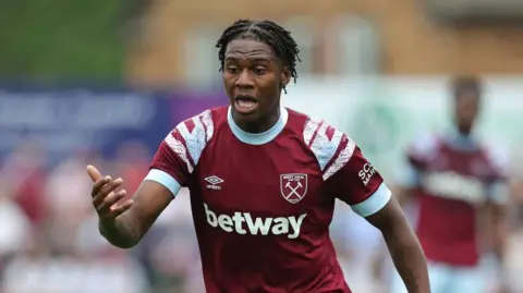 Getty Images Thierry Nevers running on a football pitch. He is wearing a West Ham football kit, which is burgundy with light blue and white features. "betway" is printed in which writing below his chest. There is an umbro logo and a West Ham logo on his shirt. The background is blurred.
