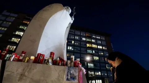 Reuters at night, the nun bends her head at the foot of a marble statue of the Pope, which was covered at the candle base.