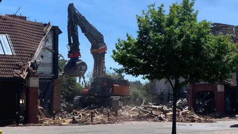 A piece of construction machinery demolishing units at a building Thurmaston Shopping Centre.