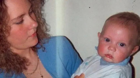 West Midlands Police Nicola Payne dressed in a blue jacket with a gold neckless holding a baby wearing white