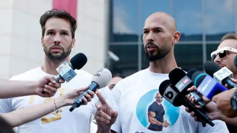 EPA Andrew en zijn broer Tristan Tate spreken met de media voor de rechtbank in Boekarest nadat het Openbaar Ministerie nieuwe beschuldigingen heeft geuit over mensenhandel en seks met een minderjarige, in Boekarest, Roemenië, 22 augustus 2024. 